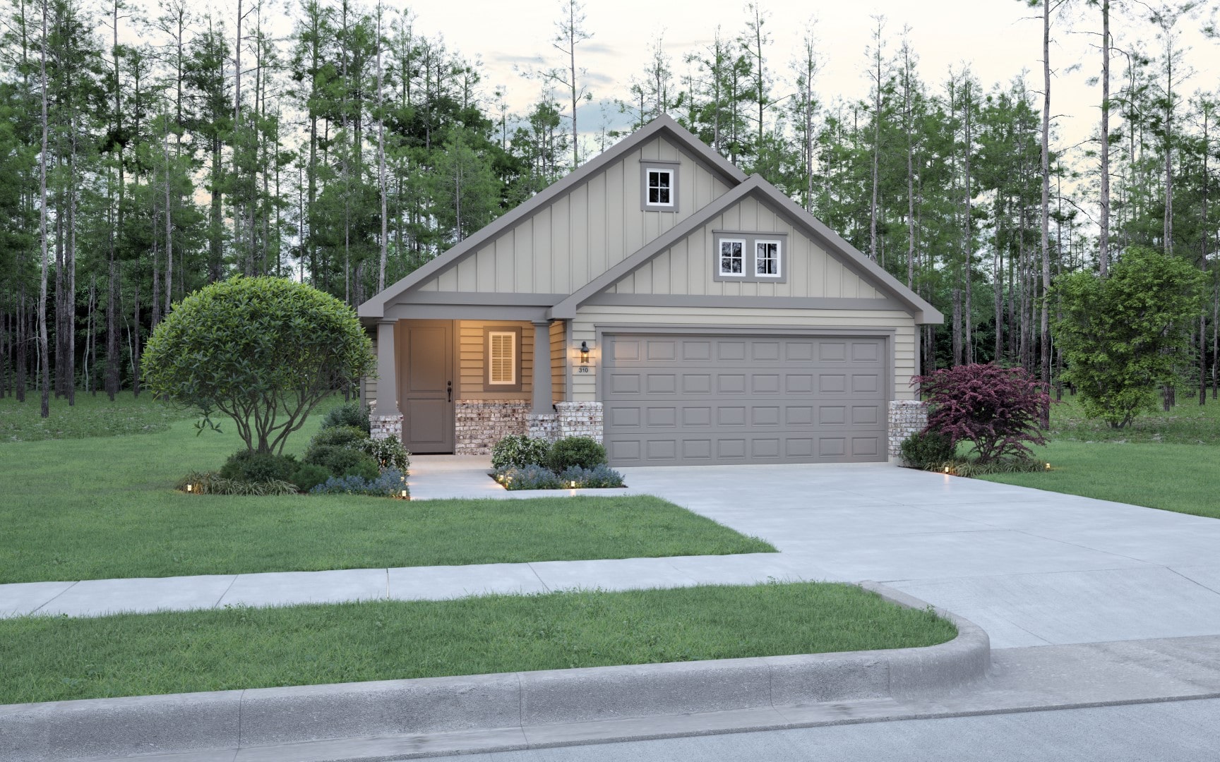 A modern single-story house with a gray garage, beige siding, and stone accents. The front yard has green grass, shrubs, and trees, with a forested background and a concrete driveway leading to the garage.