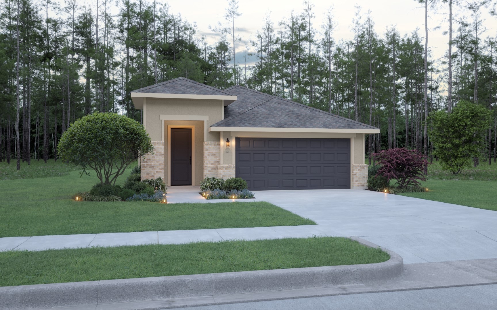 Single-story house with tan walls, brick accents, and a dark gray double garage. The front yard is landscaped with small bushes, flowers, and a tree, and a concrete driveway leads to the street. Dense trees are in the background.