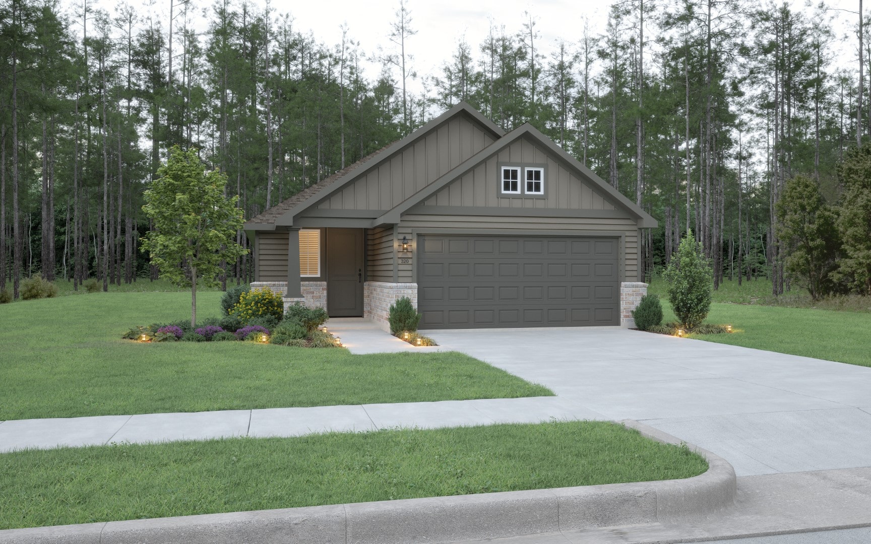 Single-story modern house with gray siding, brick accents, and a two-car garage. The home is surrounded by green grass, landscaped shrubs, and trees, with a forested area in the background.