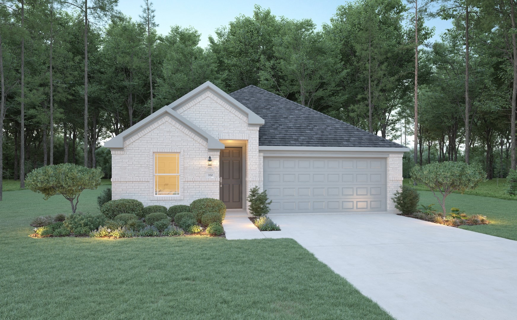 Single-story house with light brick exterior, gray shingle roof, and a double garage. The yard is landscaped with bushes, small trees, and a wide driveway. The home is surrounded by tall green trees.