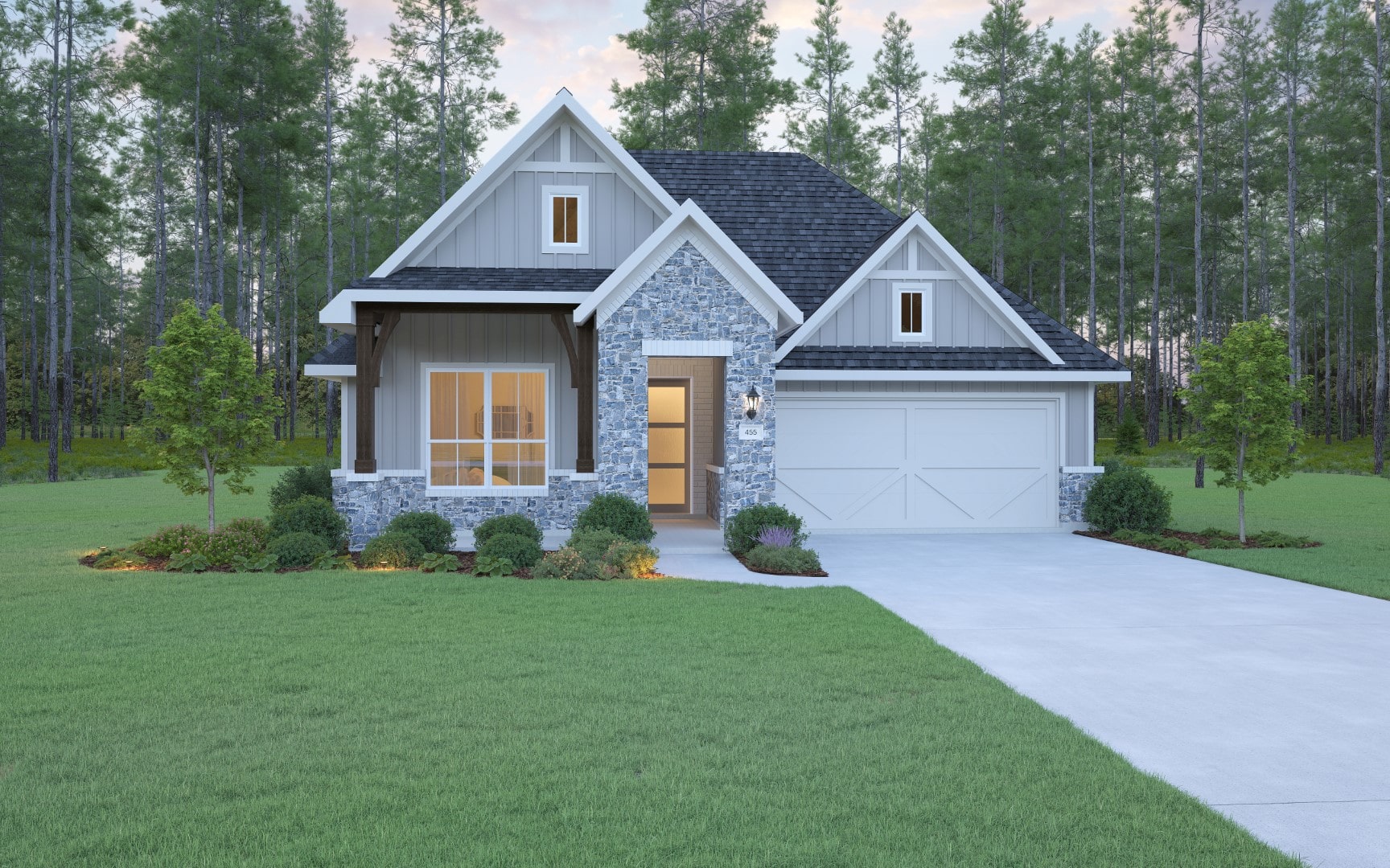 A modern single-story house with gray siding and stone accents, a front porch, white garage door, and large windows, surrounded by manicured lawn, shrubs, and trees, with a forested background.