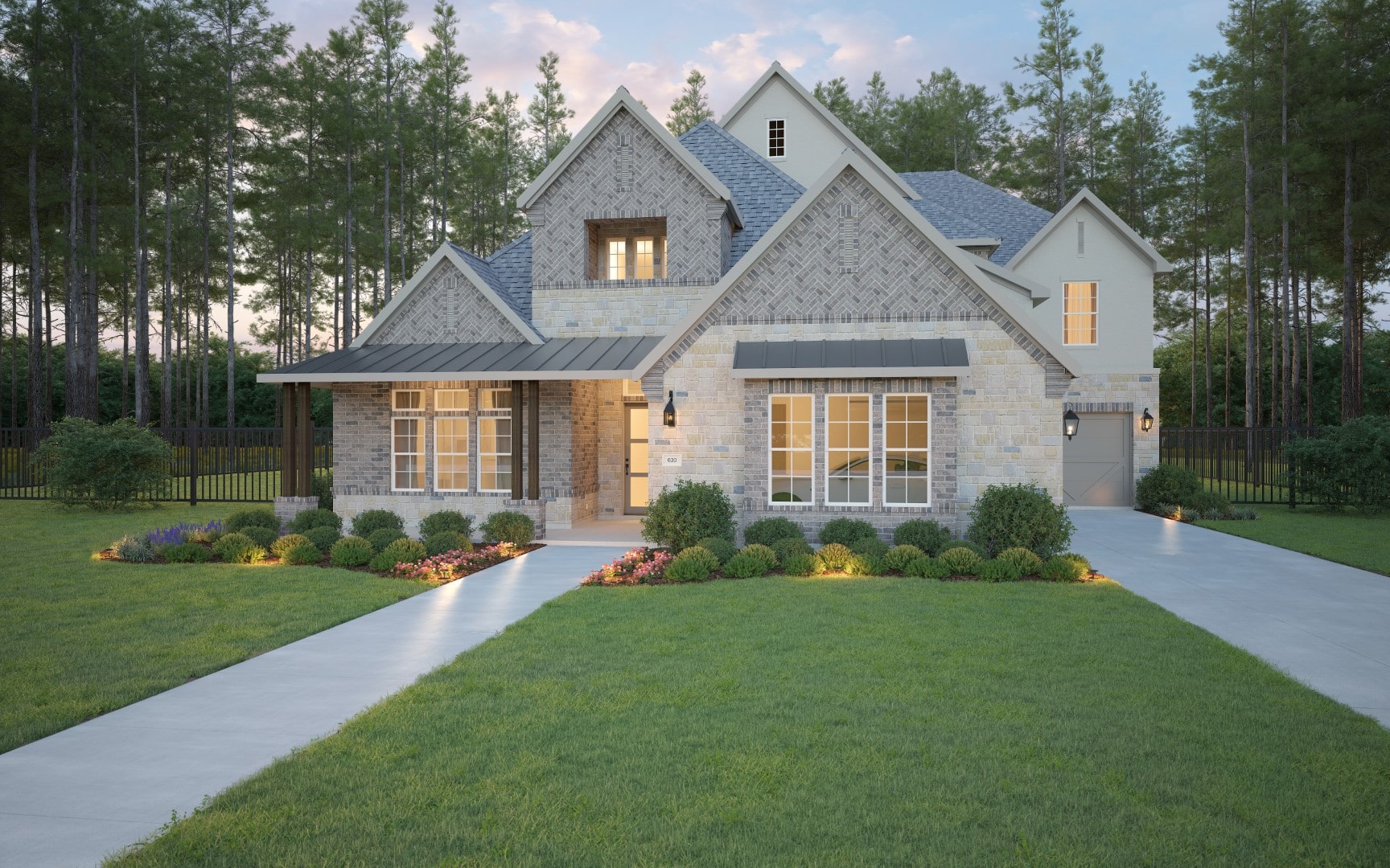 Modern two-story house with stone and brick exterior, multiple gables, large front windows, manicured lawn, flower beds, shrubs, and a driveway leading to a garage. Tall trees border the property in the background.