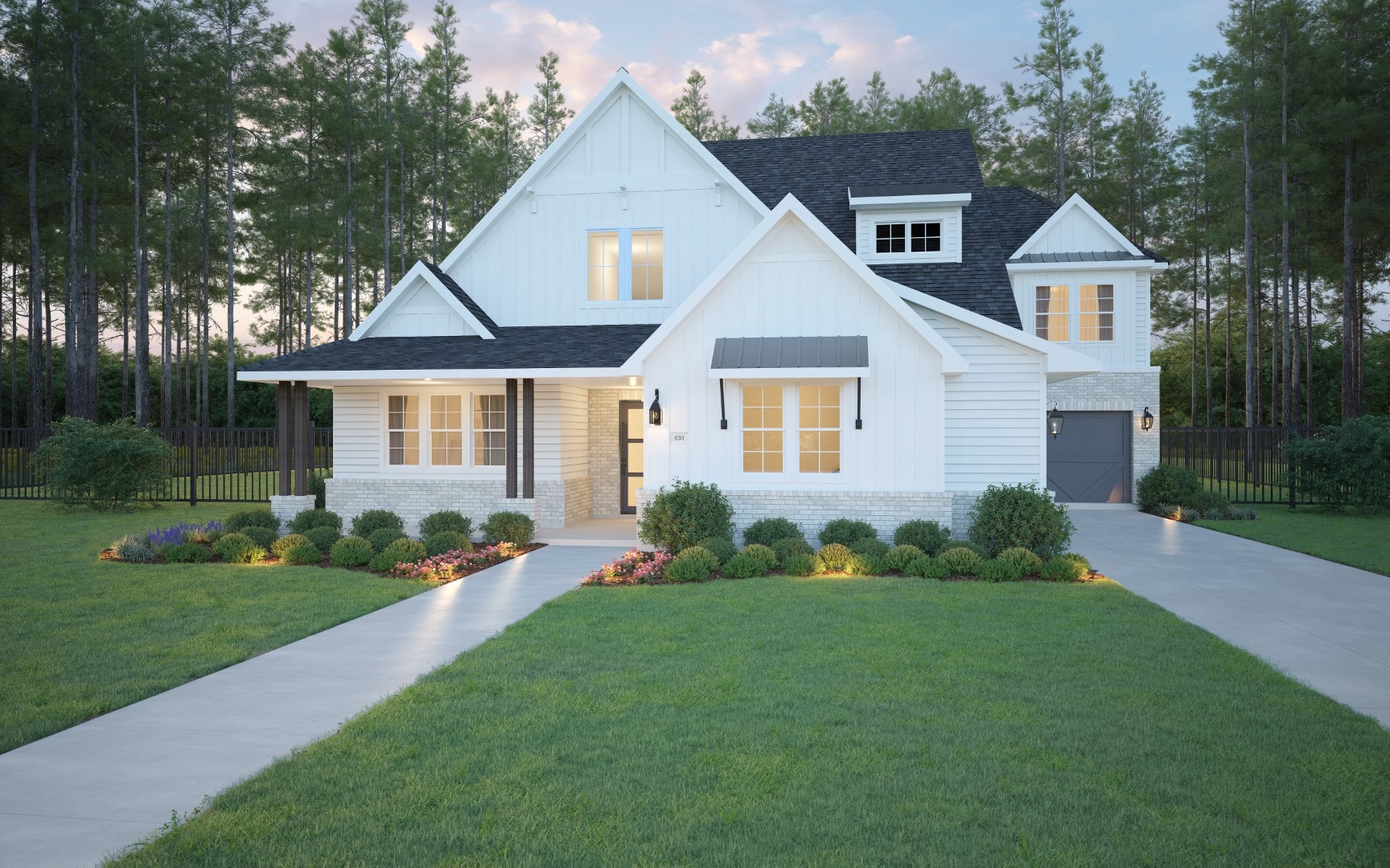 A modern white house with black roof, large windows, a covered porch, and attached garage. The front yard features green grass, manicured bushes, flower beds, and a concrete driveway, surrounded by tall pine trees.