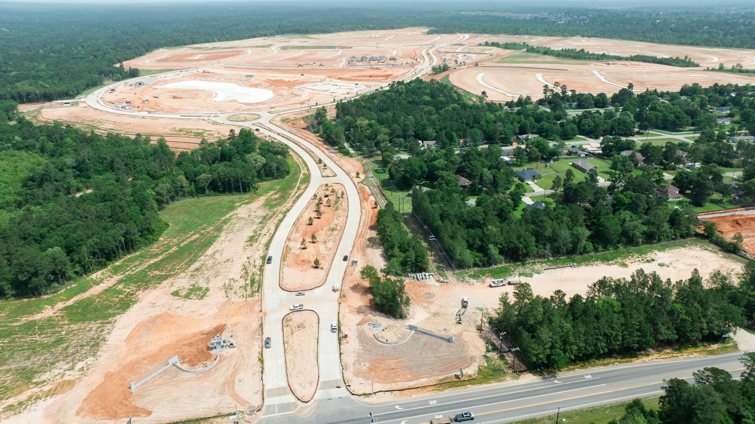Aerial view of Grand Magnolia community in Magnolia, TX through a green, forested area, with a finished roadway.